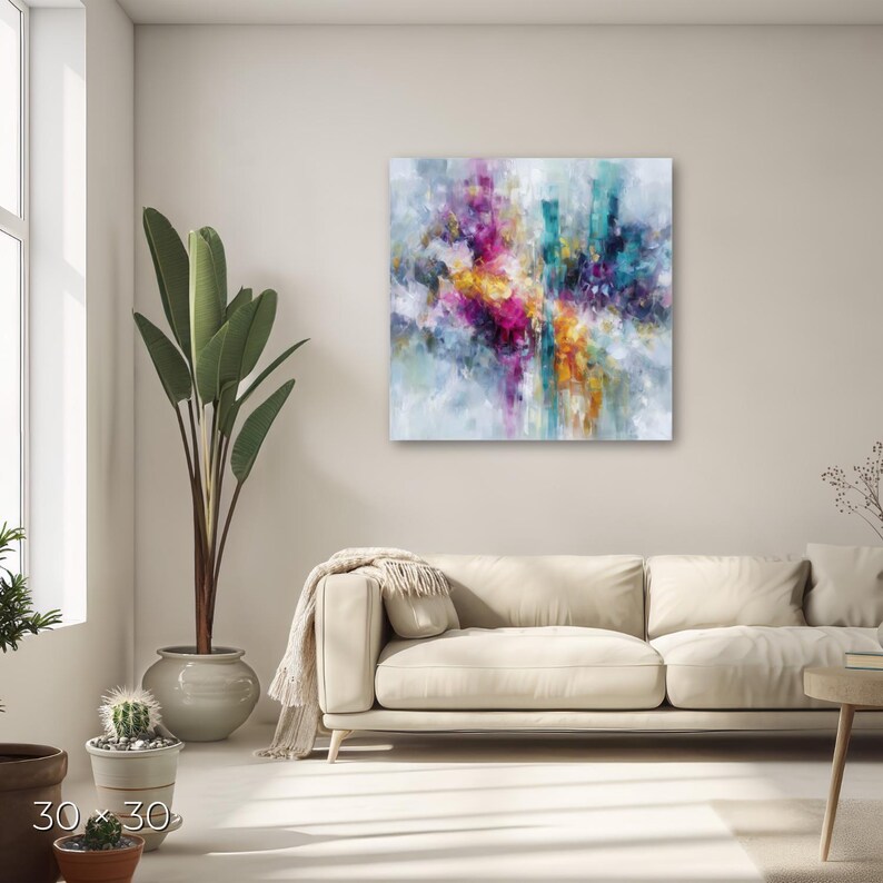 May include: A square abstract painting, 30 x 30 inches, with a vibrant display of colors. The artwork features a blend of pink, yellow, teal, and purple hues, creating a dynamic and expressive composition. The painting is mounted on a white wall above a beige sofa.