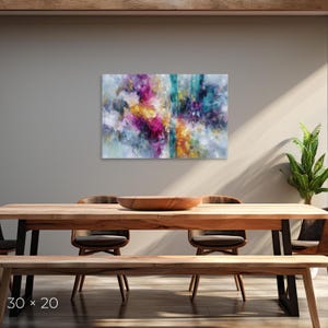 May include: Abstract art canvas print with dimensions of 30 x 20 inches. The artwork features a vibrant mix of colors, including pink, yellow, teal, and blue, creating a dynamic and expressive composition. The painting is displayed above a wooden dining table.
