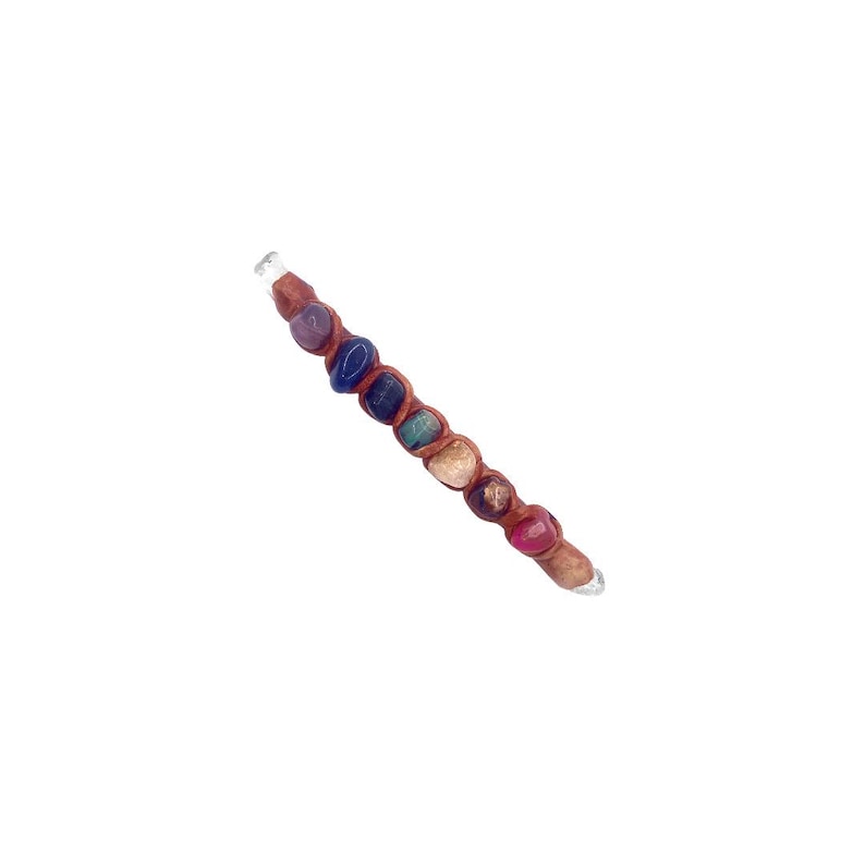 May include: A handcrafted wand featuring a series of colorful gemstones, including purple, blue, green, and red, wrapped in brown leather. The wand has a clear crystal tip and is designed for spiritual practices.