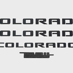 May include: Black lettering spelling out "COLORADO" in three rows, with "TRAIL BOSS" below. The letters are blocky and modern, set against a light background. The design is likely for a vehicle.