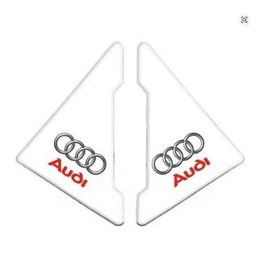 May include: Two white, triangular car accessories with the Audi logo in silver and red. The logo features four interlocking rings, and the word "Audi" is printed below.