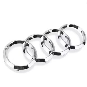 May include: A chrome emblem featuring four interlocking rings. The rings are a shiny silver color and are arranged horizontally. The emblem is likely a car logo, with a clean and modern design.