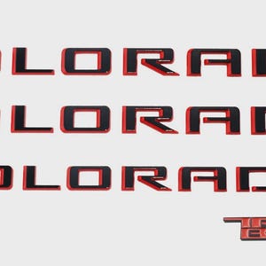 May include: Three rows of black and red "COLORADO" lettering, with a smaller "TRAIL BOSS" emblem at the bottom. The letters have a black interior and a red outline, creating a bold, eye-catching design.