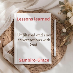 May include: A white book titled "Lessons learned" with the subtitle "Unfiltered and raw conversations with God" by Sambiro-Grace. The book rests on a woven mat, accompanied by a white pen and decorative flowers.