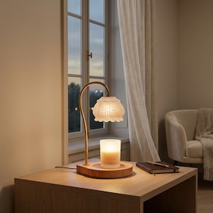 May include: A decorative table lamp with a warm, inviting glow. The lamp features a textured, bell-shaped shade and a curved, gold-toned arm. A candle sits in a wooden base, next to a notebook and pen, creating a cozy ambiance. The lamp is on a wooden nightstand.