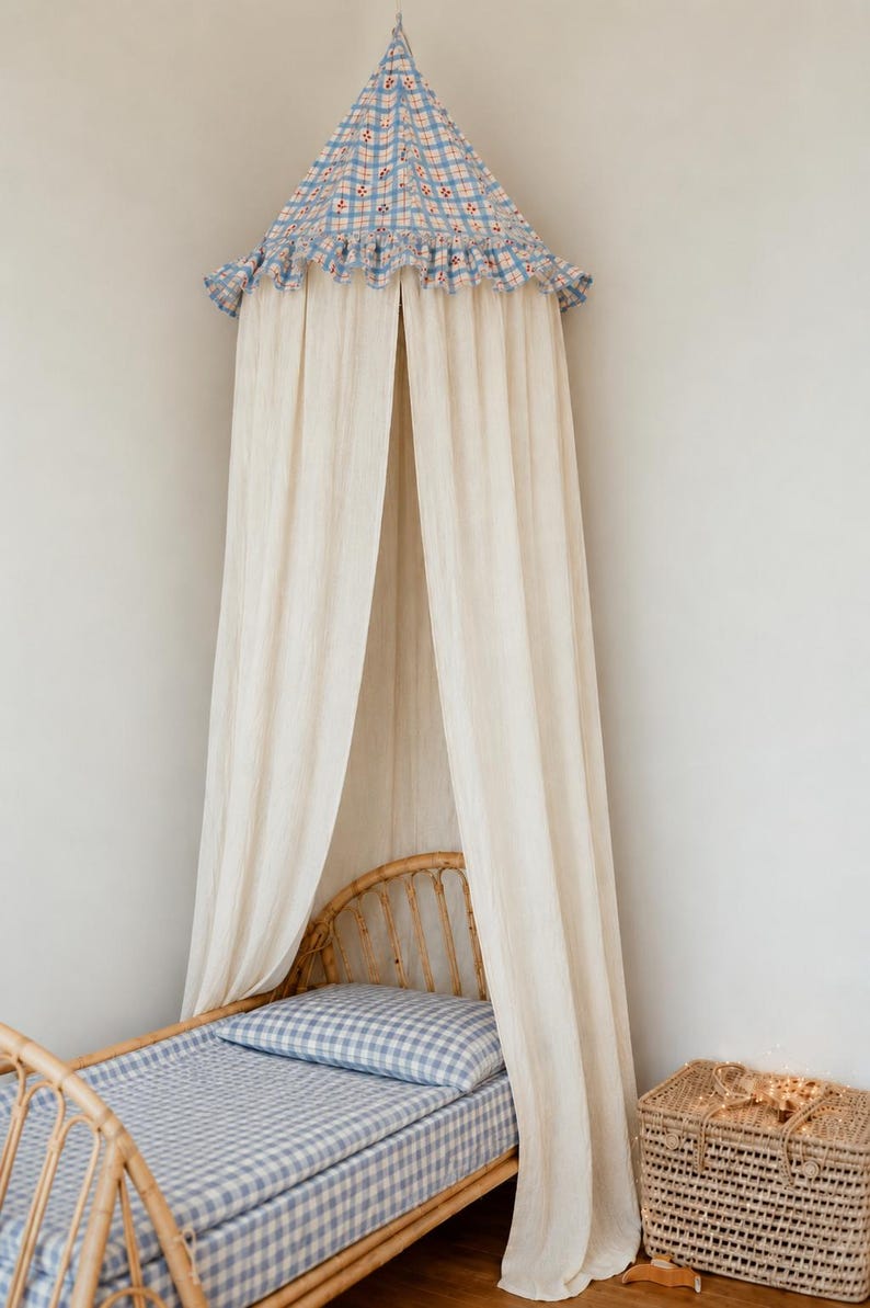 May include: A conical bed canopy featuring a blue and white checkered fabric top with a ruffled edge and long, flowing off-white curtains. The canopy is suspended above a rattan bed frame with blue and white checkered bedding and a matching pillow.