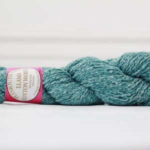 May include: A skein of teal blue yarn with a pink label that reads "Plymouth Llama Cotton Works, The Fine Line, 70% Fine Llama, 30% Cotton, A Royal Collection of Yarn".