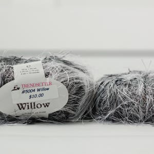 May include: Two skeins of Trendsetter Willow yarn, a blend of black and white fibers. The yarn is fluffy and textured, with a label indicating the product name and weight. The skeins are ideal for knitting or crochet projects.