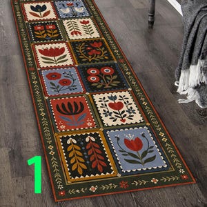 May include: A rectangular runner rug with a repeating pattern of floral designs in squares. The squares feature various flowers, birds, and leaf patterns in red, blue, and cream colours. The rug has a dark green border with floral accents.