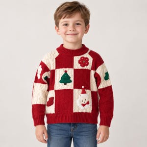 Op de afbeelding: Een gebreide trui met lange mouwen en een rood-crèmekleurig ruitpatroon. De trui is versierd met diverse applicaties, waaronder een groene kerstboom, een kerstmangezicht, een rode kerstsok, een rode bloem en een wit spookje.