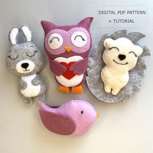 Könnte beinhalten: Handgefertigte Filz-Tierornamente: ein graues Kaninchen, eine lila Eule mit einem roten Herzen, ein weißer Igel und ein rosa Vogel. Der Text "DIGITAL PDF PATTERN + TUTORIAL" ist enthalten.