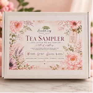 May include: A rectangular white cardboard box featuring a floral design with pink and purple flowers. The text reads Anointed Leaf Herbal Tea LLC, Tea Sampler, Loose Leaf & Tea Bag Sampler, a little of everything, and other descriptive product details.