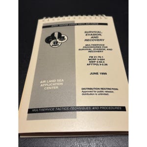 May include: A spiral-bound manual titled Survival, Evasion, and Recovery, dated June 1999. The cover is cream-colored with a gray vertical stripe, featuring military branch logos, publication codes, and the text Air Land Sea Application Center.
