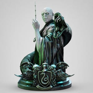 May include: A detailed figurine of a pale, bald figure in dark robes holding a thin wand, with a large, open-mouthed snake coiled around the shoulders. The base features a metallic crest with a snake emblem and the word Slytherin inscribed below.