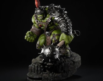 May include: A green Hulk statue in gladiator armor, holding a spiked mace. The figure has a helmet with a red plume and is posed on a rocky base. The armor is metallic, and the statue has a detailed, muscular physique.