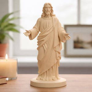 Könnte beinhalten: Beigefarbene Jesus-Statue mit ausgestreckten Armen. Die Statue steht auf einem runder Sockel. Eine brennende Kerze im Glas, ein geschlossenes Buch und eine Topfpflanze stehen auf einem Holztisch. Religiöses Objekt.
