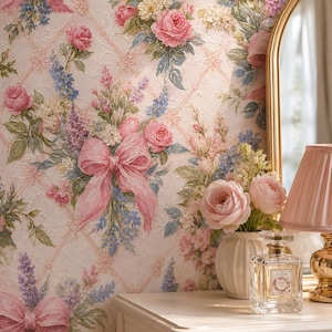 May include: Wallpaper featuring a textured lattice pattern with pink bows and bouquets of pink roses and blue flowers. A white fluted vase with pink roses, a glass perfume bottle, and a pink pleated lamp sit on a white wooden dresser.