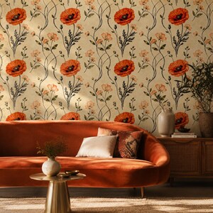 May include: A living room scene featuring a burnt orange velvet sofa, a small gold side table, and a wooden cabinet. The wallpaper has a floral pattern of red poppies and delicate vines. Decorative pillows and vases add to the room's aesthetic.