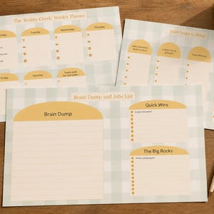 May include: A selection of weekly planners and job lists in a light blue and cream colour scheme. The planners feature sections for daily tasks and reminders. The text "The Reality Check Weekly Planner" and "Brain Dump and Jobs List" are visible.