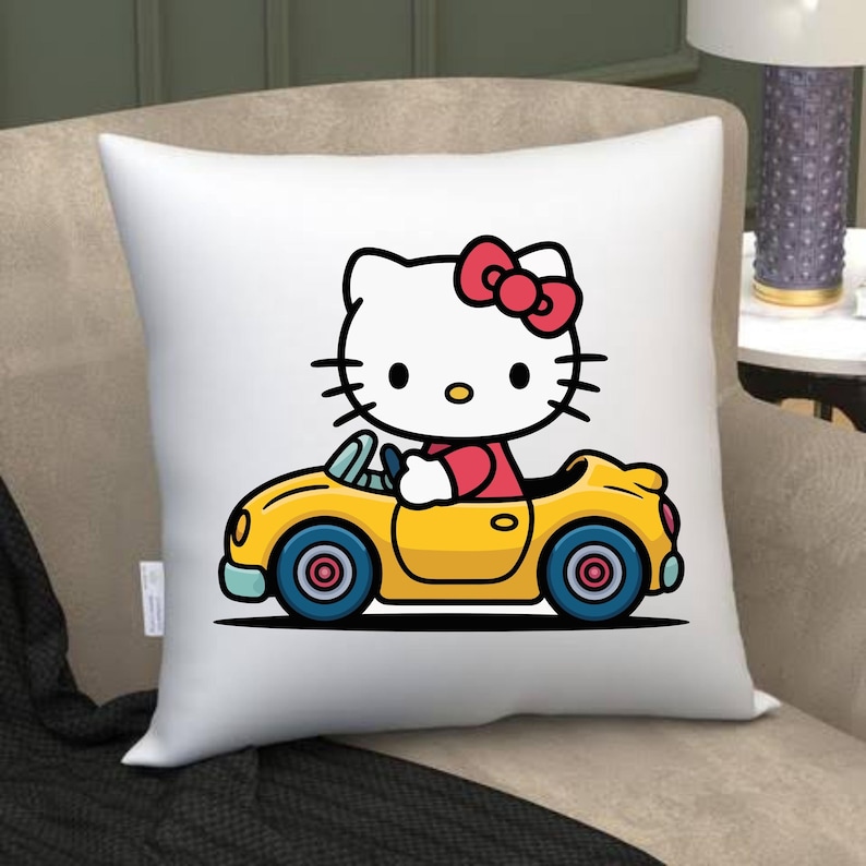 May include: White square pillow featuring a cartoon image of Hello Kitty driving a yellow convertible car. Hello Kitty has a red bow and is wearing a red top. The car has blue wheels and a black outline.