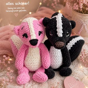Könnte beinhalten: Zwei gehäkelte Stinktier-Stofftiere. Eines ist rosa und weiß mit schwarzen Akzenten, das andere ist schwarz und weiß. Der Text lautet: Gemeinsam ist alles schöner! Sammy hat seine rosa Herzensfreundin gefunden. Beide haben große dunkle Augen und weiche Texturen.