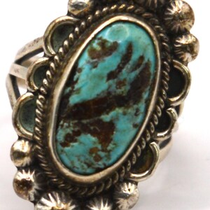 Puede incluir: Un anillo de plata con una piedra turquesa de forma ovalada con patrones de matriz de color marr&oacute;n oscuro. La piedra est&aacute; rodeada por un borde de cuerda trenzada y un borde festoneado adornado con peque&ntilde;as cuentas de plata redondas.