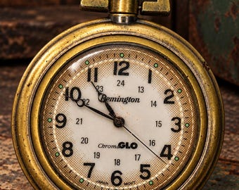 Reloj de bolsillo Remington ChromaGLO antiguo, esfera luminosa en funcionamiento, 24 horas, tono latón, movimiento japonés, 1,75 pulgadas.