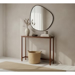 May include: A modern interior scene featuring a dark wood console table with a decorative mirror. The table holds a vase with dried plants, books, and a small bowl. A woven basket sits below, and a beige rug lies on the floor.