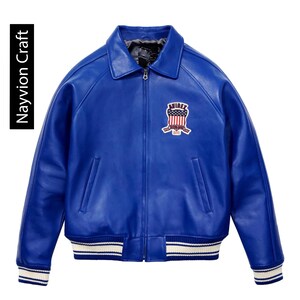 May include: A vibrant blue leather jacket with a classic bomber style. Features a zip-up front, a collared neckline, and a patch on the chest with a red, white, and blue design. The cuffs and hem have white stripes. The text "Navyion Craft" is on the left side.