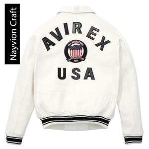 May include: Cream-colored bomber jacket with black and white striped cuffs and hem. The back features the word "AVIREX" above a circular emblem with "ALL AMERICANS ESTABLISHED 1975" and a USA flag design. Below is the word "USA".