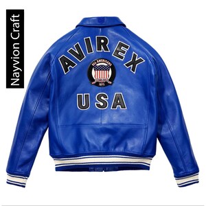 May include: A vibrant blue leather jacket with the word "AVIREX" across the back, along with a patch featuring the American flag and the word "USA". The jacket has a classic bomber style with white and blue striped cuffs and hem.