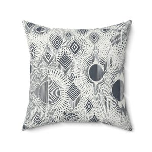 May include: Square throw pillow with a geometric pattern in shades of gray and white. The design features diamond shapes, sunbursts, and dotted lines. The pillow is a decorative accent for a sofa or bed.
