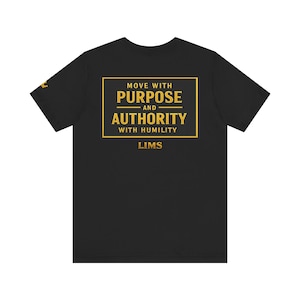 以下が含まれることがあります： 金色のテキストが入った黒いTシャツ。「MOVE WITH PURPOSE AND AUTHORITY WITH HUMILITY」というテキストが金色の長方形の中にあります。「LIMS」という単語が下にあります。