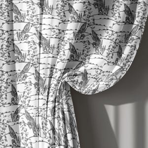 Puede incluir: Una cortina blanca con un estampado botánico negro repetitivo de hojas delgadas y enredaderas finas. La tela está recogida en pliegues suaves, creando un efecto drapeado con pliegues verticales que resaltan el intrincado patrón de líneas oscuras.
