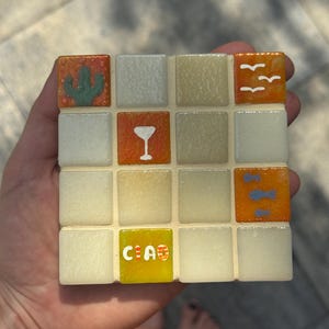 Peut inclure: Un dessous de verre mosaïque carré composé de seize carreaux disposés en grille quatre par quatre. Les carreaux présentent un mélange de verre translucide blanc cassé, orange et jaune. Les motifs incluent un cactus vert, un verre à cocktail blanc, des oiseaux blancs, des poissons bleus et le mot CIAO en lettres blanches.