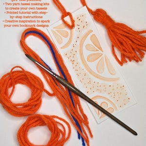 May include: A craft kit for making bookmarks and tassels. The kit includes bookmark blanks, orange yarn, blue yarn, a paintbrush, and a printed tutorial. The bookmark design features orange slices. The text on the image says "This Kit Includes" and "Upcrafted Bookmark Workshop - Bookmark + Tassel Maker Kit".