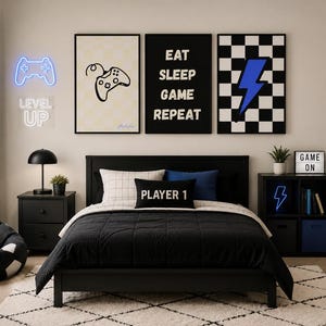 May include: A bedroom set featuring a black bed frame with black bedding and a black pillow labeled PLAYER 1. Three wall art prints display a game controller, the text EAT SLEEP GAME REPEAT, and a blue lightning bolt on a checkered background.