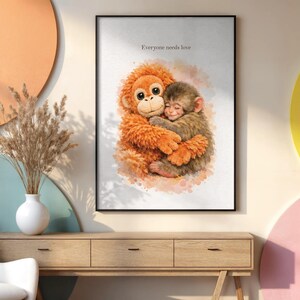 Peut inclure: Une affiche encadrée avec une illustration à l'aquarelle de deux singes qui s'embrassent. Le plus grand singe est orange, le plus petit est brun. Le texte "Everyone needs love" est en haut. L'œuvre est sur une console en bois.