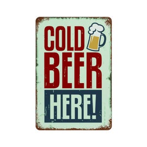 以下が含まれることがあります： 古びた仕上げの長方形の金属看板。「COLD BEER HERE！」の文字が赤と白の太字で、ビールのジョッキのグラフィックが描かれています。背景は明るい緑色です。