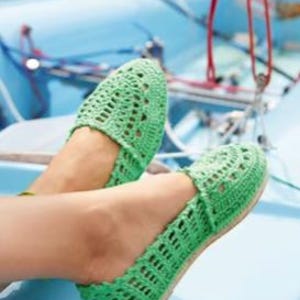 May include: A white ceramic mug with a black handle and the text "But First, Coffee" in a bold, black font. The mug is set against a blurred background, suggesting a cosy setting.