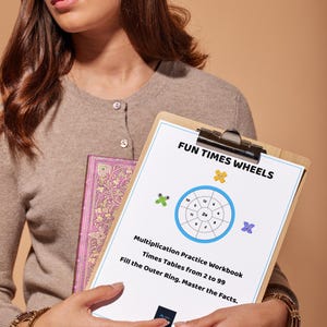Puede incluir: Un portapapeles de madera que sostiene una hoja de papel blanca titulada FUN TIMES WHEELS. La página presenta un diagrama de multiplicación circular azul, personajes de dibujos animados y el texto Multiplication Practice Workbook.