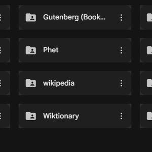 Könnte beinhalten: Eine weiße Keramik-Tasse mit schwarzem Henkel und dem Text "But First, Coffee" in fetter, schwarzer Schrift. Die Tasse steht vor einem verschwommenen Hintergrund, der eine gemütliche Umgebung suggeriert.