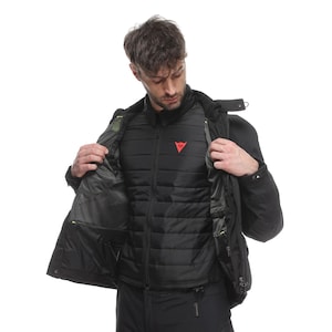 May include: Black motorcycle jacket with a quilted inner layer and a red logo on the chest. The jacket has multiple pockets and a high collar. The model is wearing black trousers.