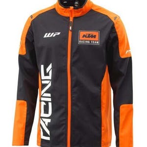 Puede incluir: Chaqueta de carreras negra y naranja con cremallera completa. La chaqueta presenta el texto "RACING" en blanco en la parte delantera, junto con el logotipo "KTM Racing Team". Tiene detalles en naranja en hombros, mangas y laterales.