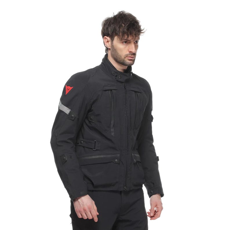 May include: Black motorcycle jacket with multiple pockets, a high collar, and a red logo on the shoulder. The jacket has reflective stripes on the sleeve and a zippered front closure. The jacket appears to be made of a durable, weather-resistant material.