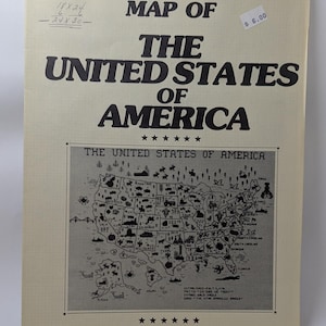 May include: A cream-colored counted cross stitch chart titled MAP OF THE UNITED STATES OF AMERICA. The paper features black text, a central map illustration with state-specific icons, and the designer name Joanne K. Overstreet at the bottom.