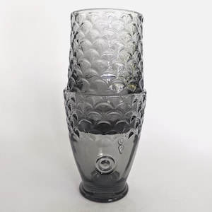 Peut inclure: Deux verres à boire gris empilés. Les verres présentent un motif texturé en forme d'écailles. Le verre du bas a un motif circulaire près de la base. Verres en verre.