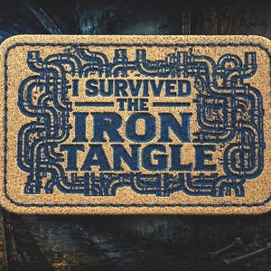 May include: A rectangular patch with a tan textured background and a dark blue embroidered border. The center features the text I SURVIVED THE IRON TANGLE in blue, surrounded by a complex, interconnected pattern of blue pipes and industrial conduits.