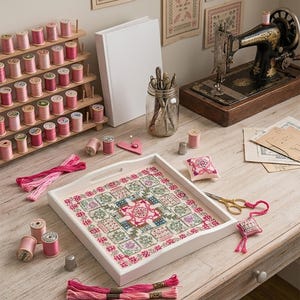 May include: A craft table displays a white tray with a cross-stitch design, spools of pink thread, embroidery floss, a vintage sewing machine, and a jar of tools. The scene is set for needlework and crafting.