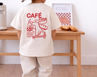 Camiseta infantil Cafe Cove, estampado de café con perro en patineta, camiseta unisex para niños, color beige.